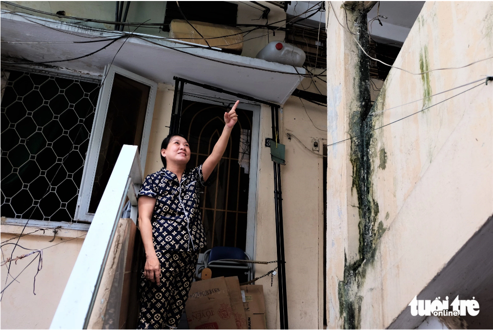 Lan Anh, a resident at the apartment building at 137 Ly Thuong Kiet Street, points at a downgraded wall at the building. Photo: Phuong Nhi / Tuoi Tre