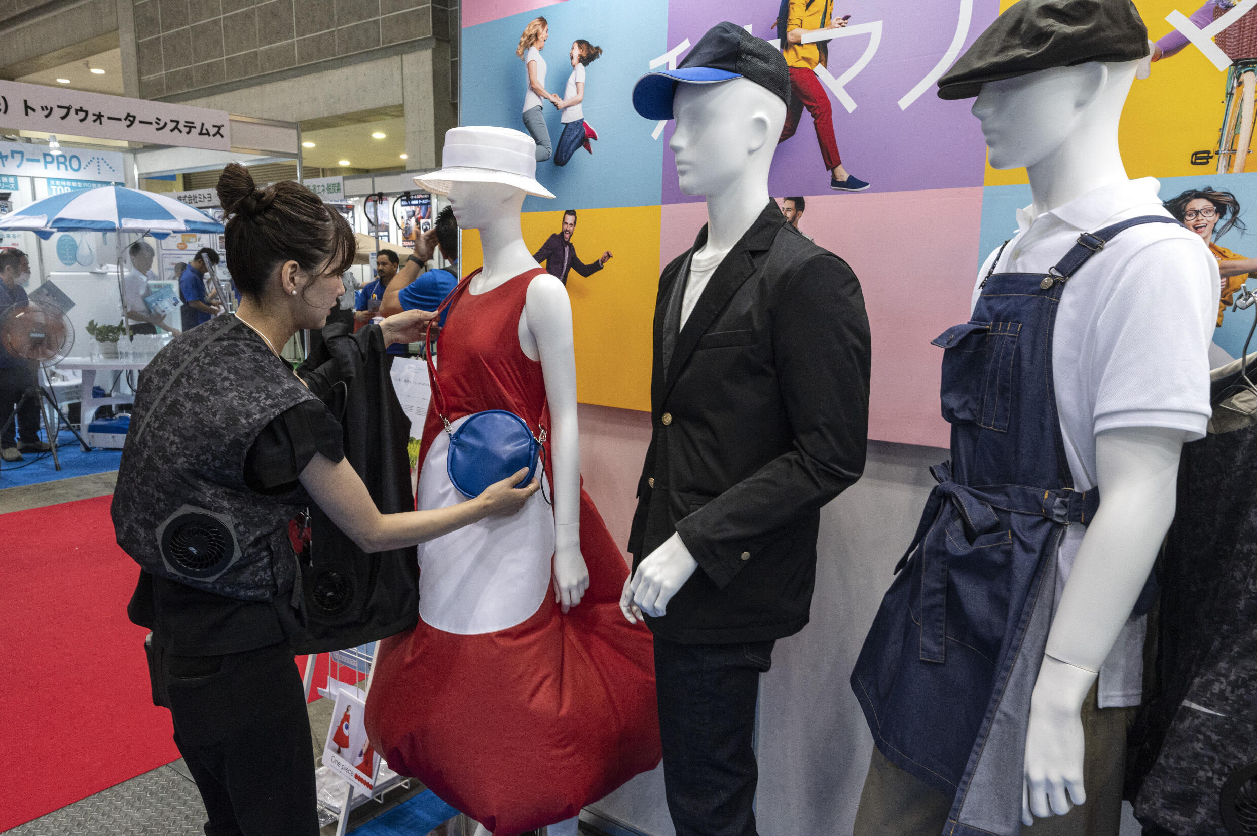 This photo taken on July 27, 2023 shows a staff member adjusting lifestyle clothing designed to battle heat on display by Chikuma & Co., during the 'Tokyo Extreme Heat Countermeasures Exhibition' during Techno Frontier 2023 at the Tokyo Big Sight venue in Tokyo. Photo: AFP