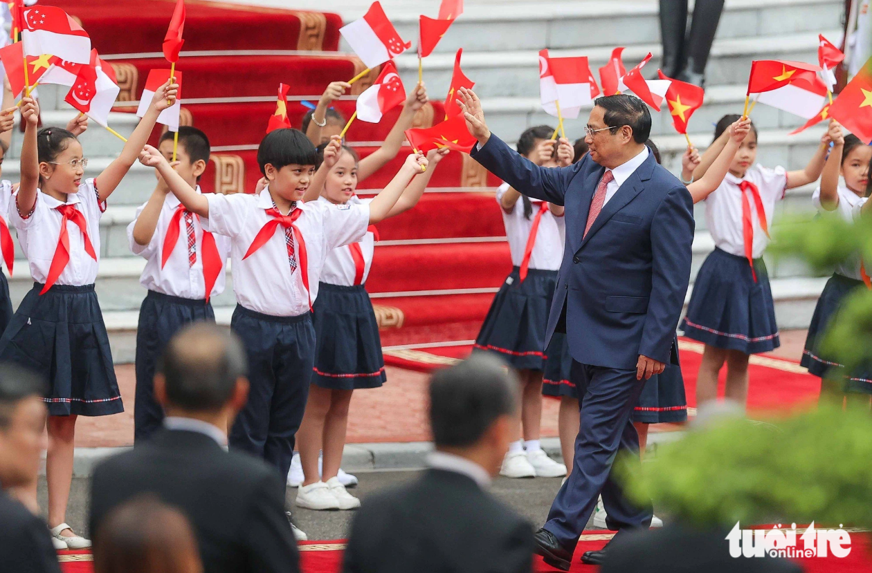 Prime Minister Pham Minh Chinh waves to children at the welcome ceremony for Singaporean Prime Minister Lee Hsien Loong on August 28, 2023. Photo: Nguyen Khanh / Tuoi Tre