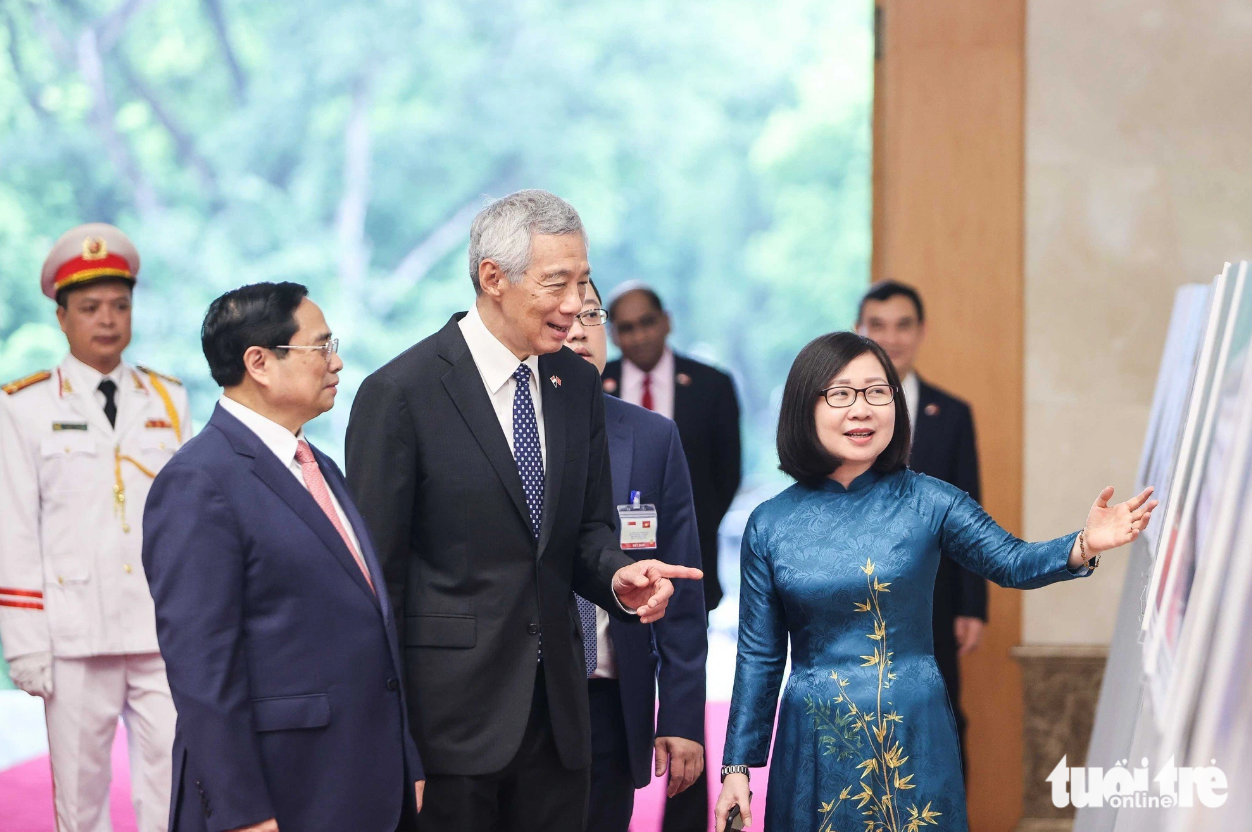 Prime Minister Pham Minh Chinh (L) and his Singaporean counterpart Lee Hsien Loong (C) take a look at some photos of the two nations’ 50-year ties on display at the Government Office. Photo: Nguyen Khanh / Tuoi Tre
