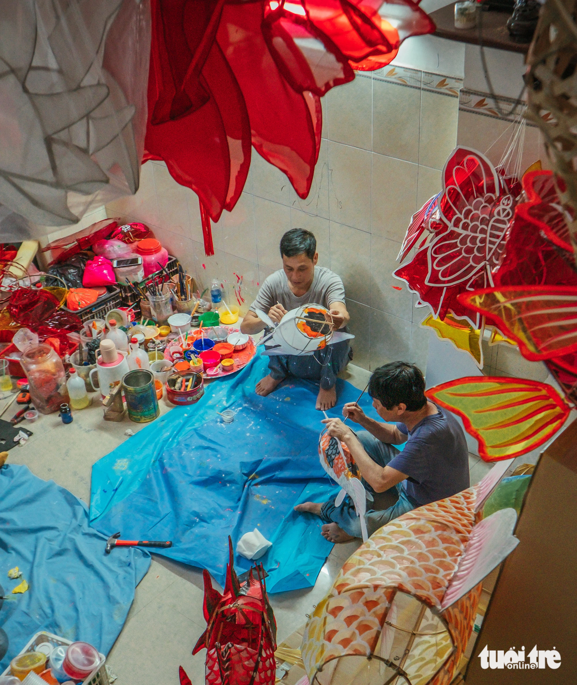 Two artisans decorate lanterns.