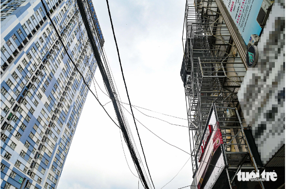 Two adjacent buildings are equipped with escape ladders, creating a metal layer on their façades. Photo: Hong Quang / Tuoi Tre