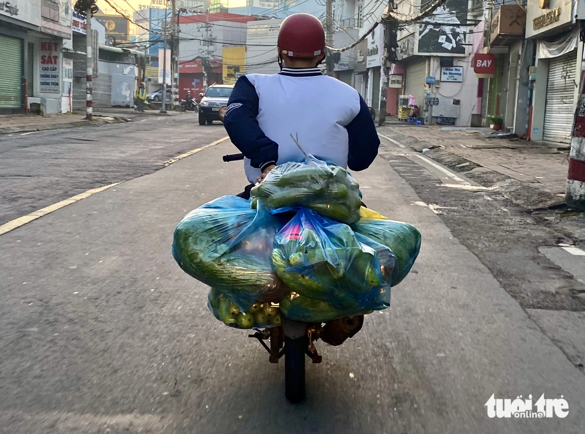 A man is seen transporting many plastic bags containing vegetables on Vo Van Ngan Street in Thu Duc City under Ho Chi Minh City
