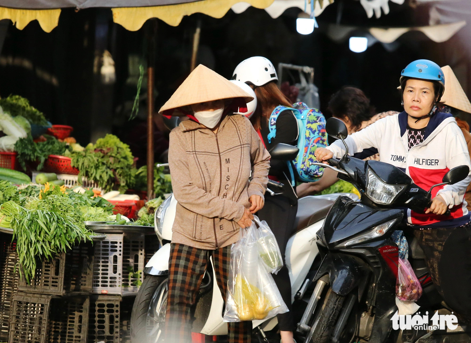 Market-goers carry items contained in plastic bags