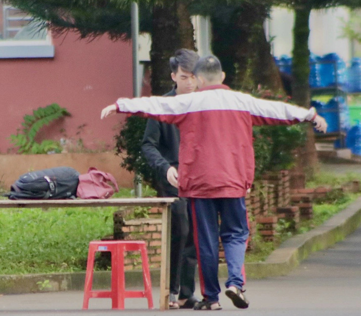 A school staff member uses a metal detector to search a student. Photo: The The / Tuoi Tre