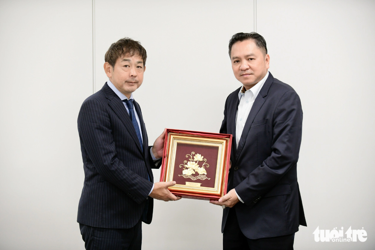 Pham Huy Binh (R), chairman of Saigontourist Group, hands a picture of lotus to Yoshiro Tanaka, deputy editor-in-chief of Mainichi. Photo: Quang Dinh / Tuoi Tre