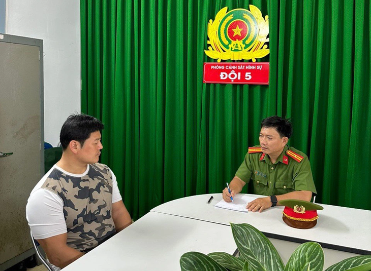 A police officer questions Son Tea Heum (L), the owner of Luxury Business Club. Photo: Supplied by Ho Chi Minh City Police
