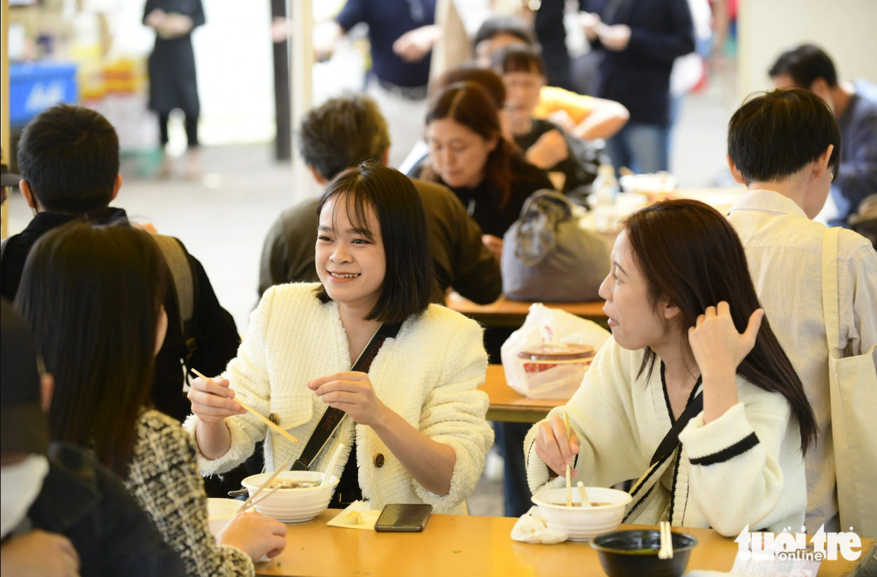 Vietnamese people living in Tokyo are pictured chatting while eating pho. Photo: Tuoi Tre