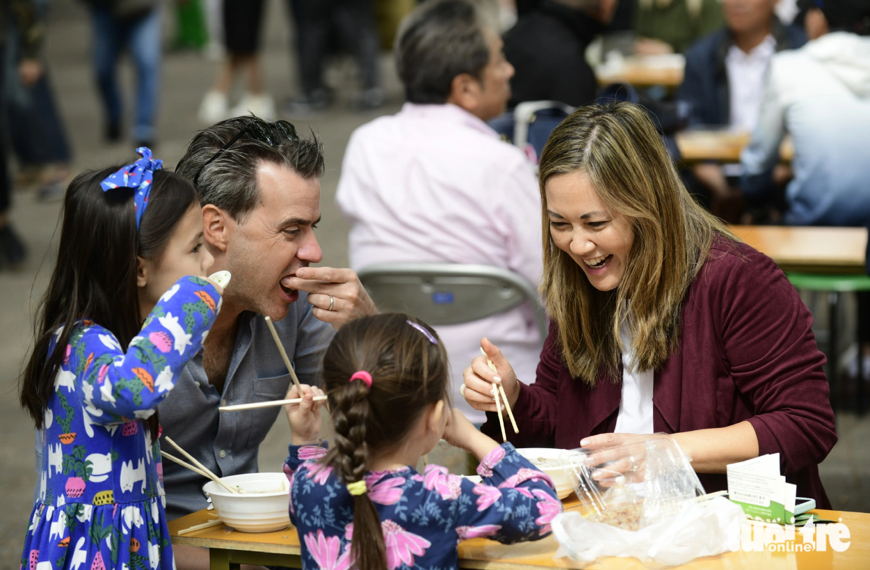 Bich Hang, a Vietanmese Australian, and her family members savor pho at Yoyogi Park, Tokyo on October 8, 2023. She said that her family has moved to Japan for a year, adding that after hearing about the launch of the Vietnam Phở Festival 2023 in Japan, she quickly planned a trip to join the cuisine event. Photo: Tuoi Tre