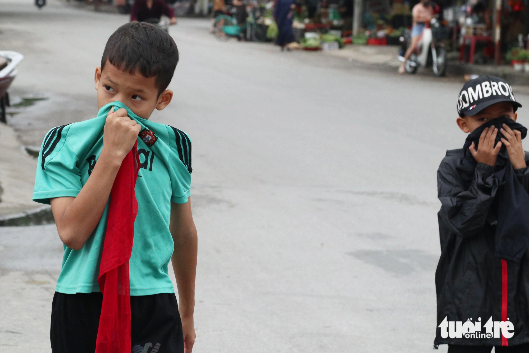 Students on their way home from school are seen covering their noses due to the stinky smell of dead fish in the moat. Photo: Doan Hoa / Tuoi Tre