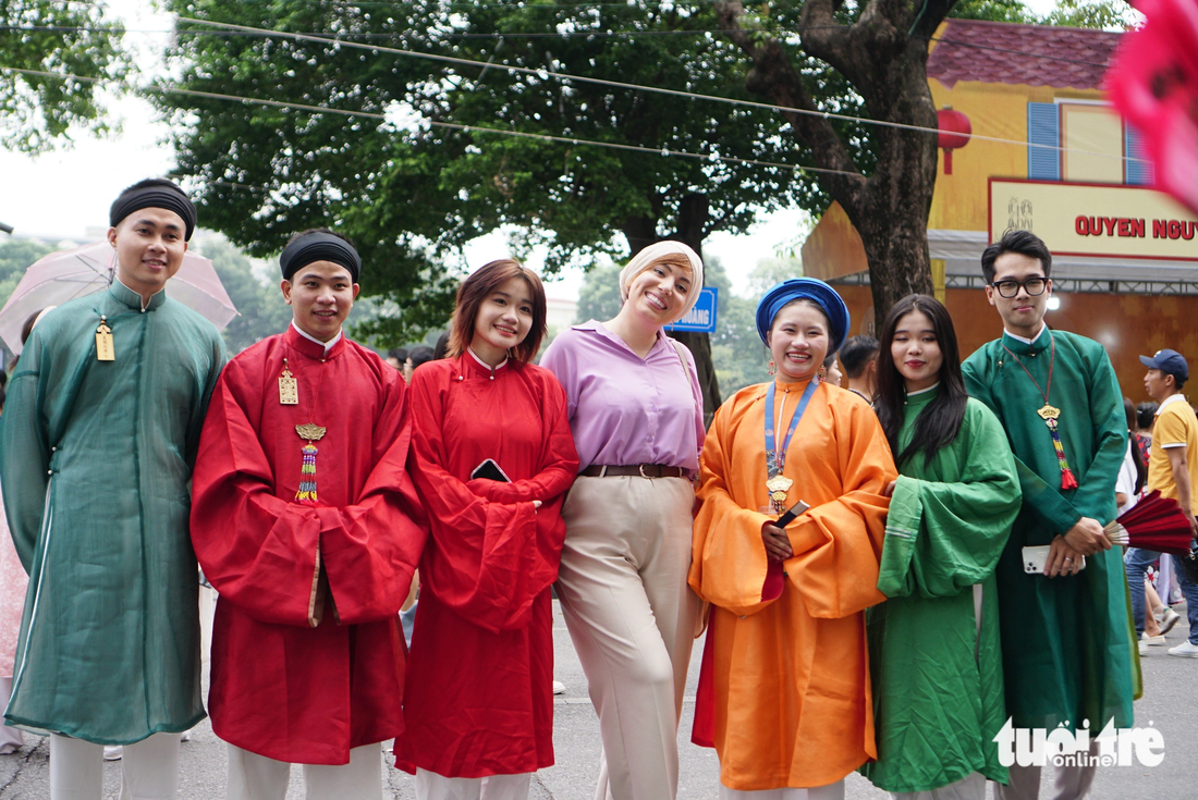 A foreign tourist (L, 4th) poses for a photo with young people donning ‘ao dai’ (Vietnam's traditional costume) in Hanoi on October 28, 2023. Photo: Nguyen Hien / Tuoi Tre