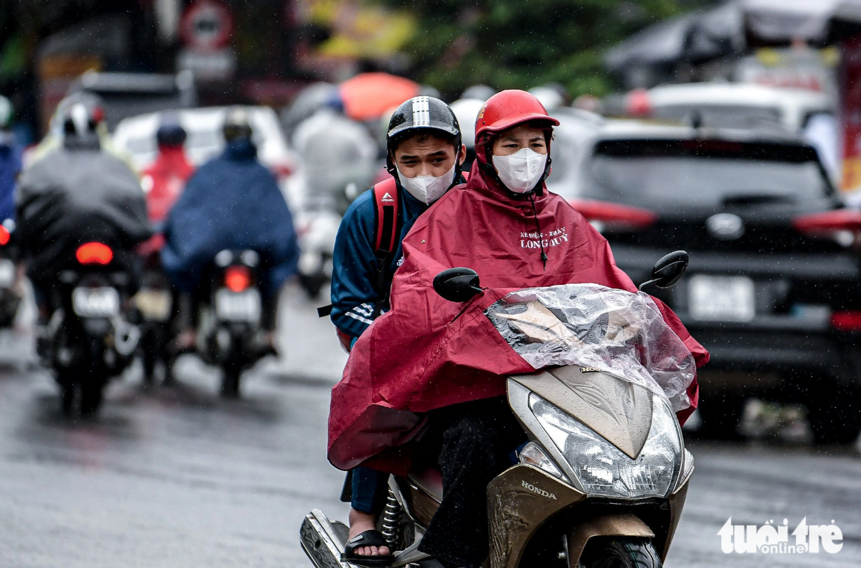 Commuters stoop in the cold wind and rain. Photo: Nam Tran / Tuoi Tre