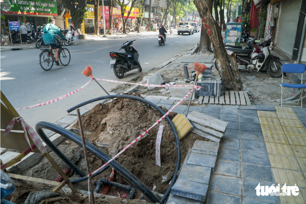 The sidewalk is a construction site, affecting residents’ traveling and business activities. Photo: Pham Tuan / Tuoi Tre