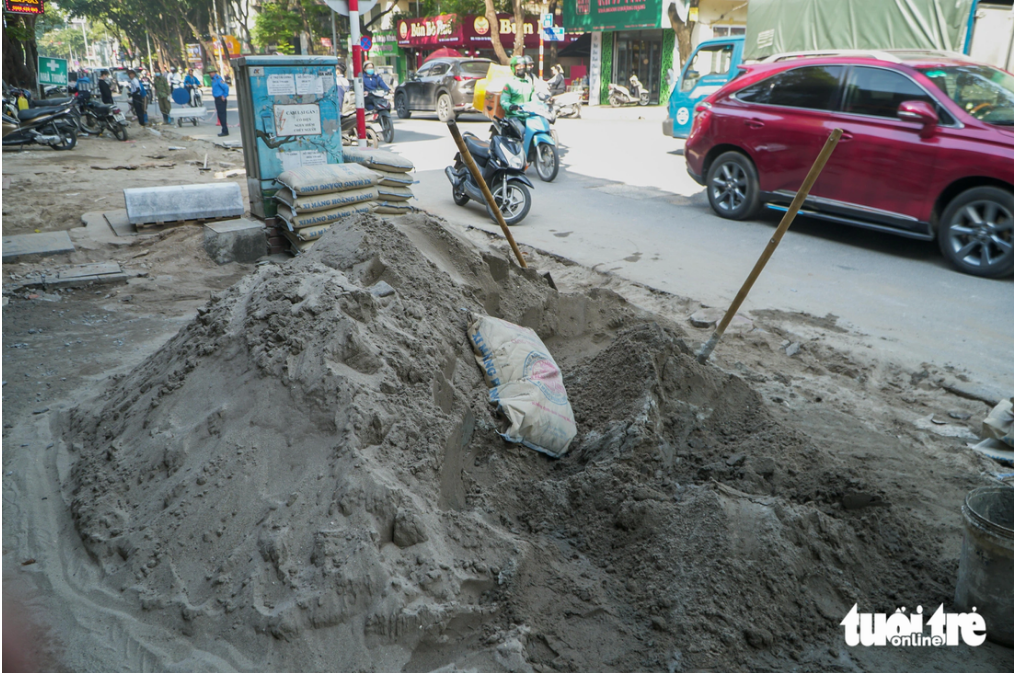A large heap of cement mixed with sand on a sidewalk, impeding locals’ traveling. Photo: Pham Tuan / Tuoi Tre