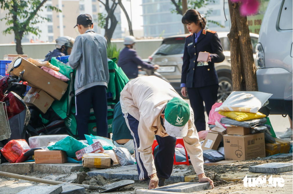 Workers repave the sidewalk of Pham Van Bach Street in Hanoi. Photo: Pham Tuan / Tuoi Tre