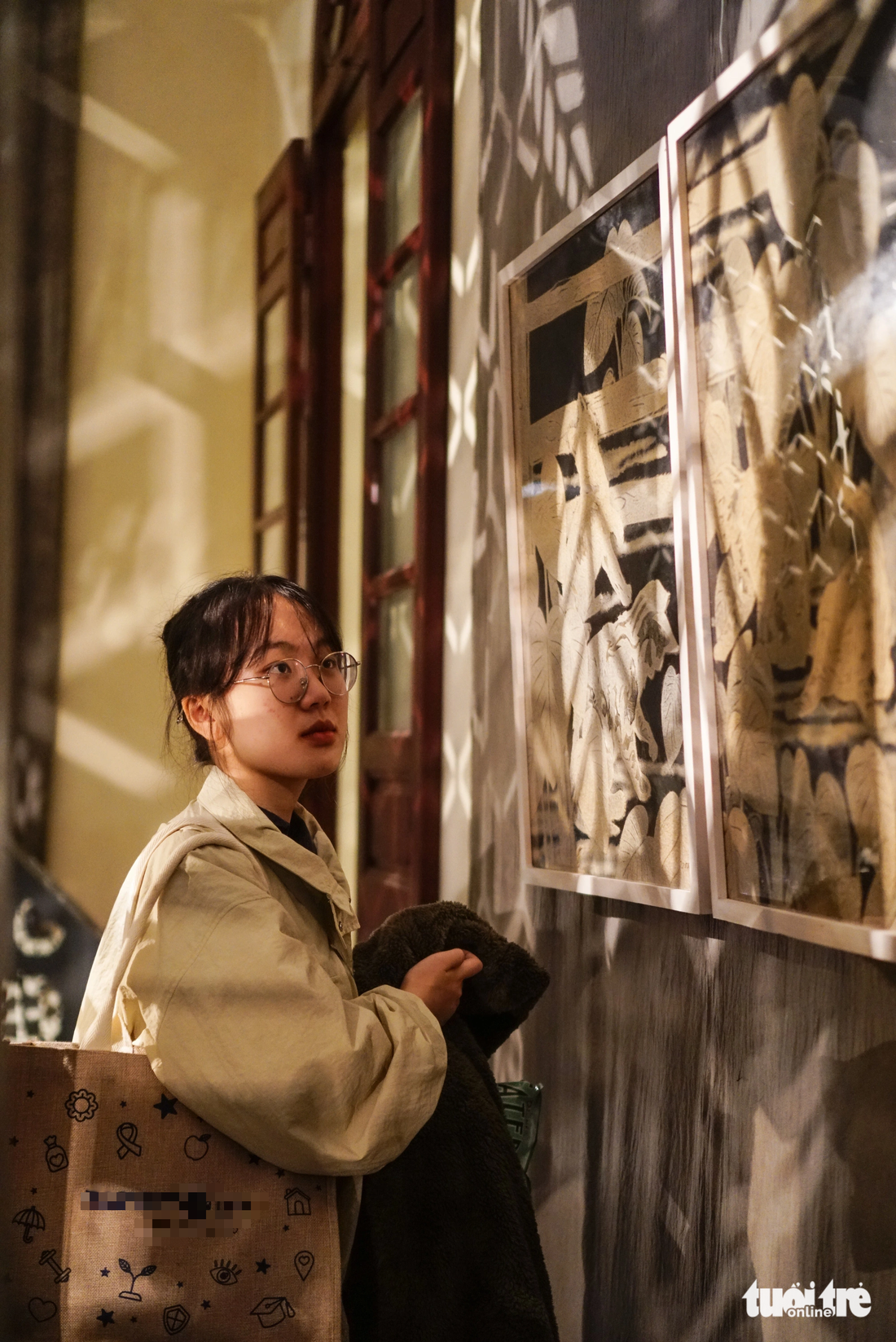 A girl watches ‘truc chi’ paintings on display at 22 Hang Buom Cultural and Arts Center in Hanoi. Photo: Nguyen Hien / Tuoi Tre