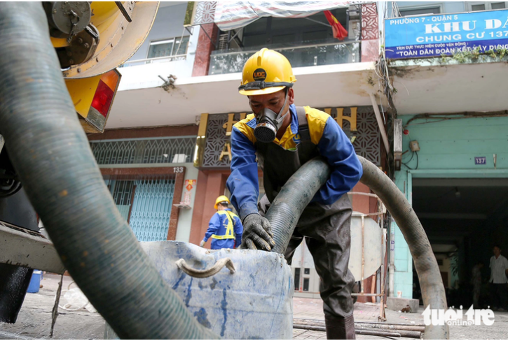 A worker uses a specialized machine to suck waste oil, fat and grease from a sewer. Photo: Phuong Quyen / Tuoi Tre