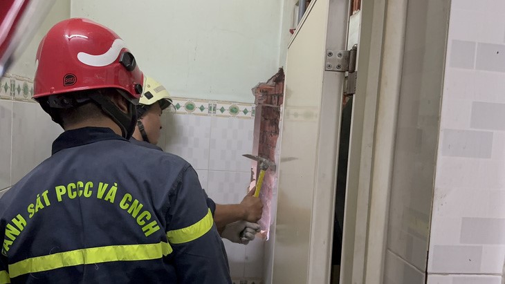 A rescuer uses a hammer to break the wall to save the victim.