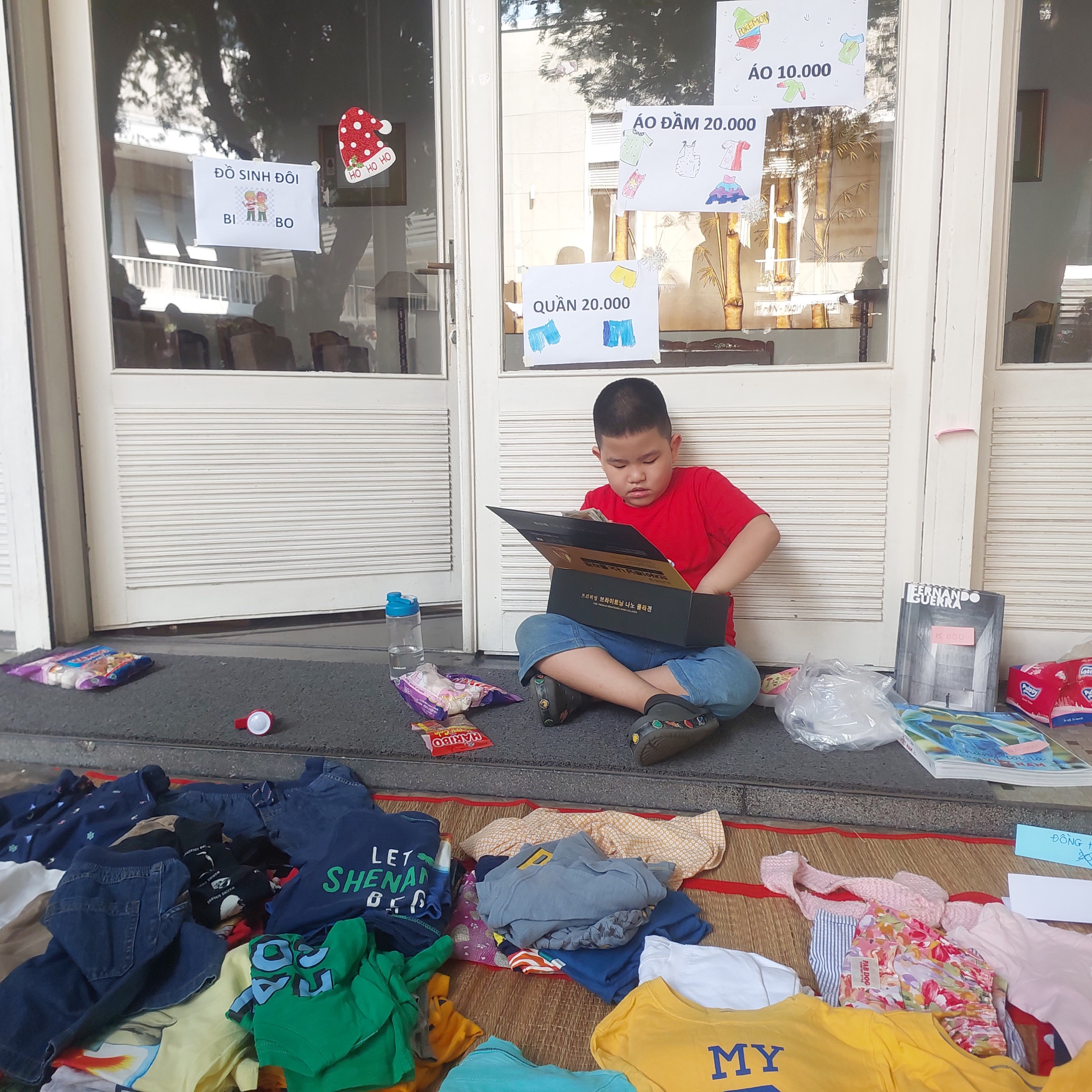 A little boy helps his mother look after the clothing counter. Photo: Minh Chau / Tuoi Tre News