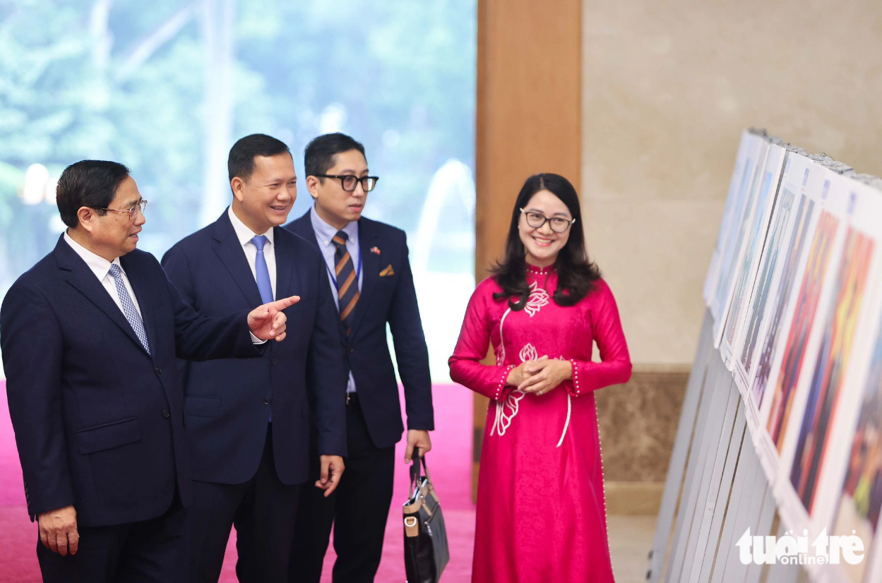 The two Vietnamese and Cambodian premiers take a look at photos describing the two nations’ ties. Photo: Nguyen Khanh / Tuoi Tre