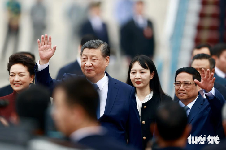 Vietnamese Prime Minister Pham Minh Chinh (waving hand, R) welcomes Chinese Party General Secretary and President Xi Jinping (waving hand, L) at the airport. Photo: Nguyen Khanh / Tuoi Tre