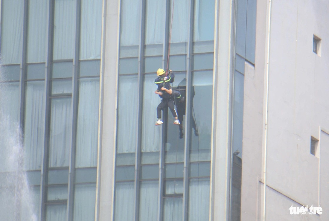 A firefighter helps a customer of a hotel near the metro station reach the ground. Photo: Minh Hoa / Tuoi Tre