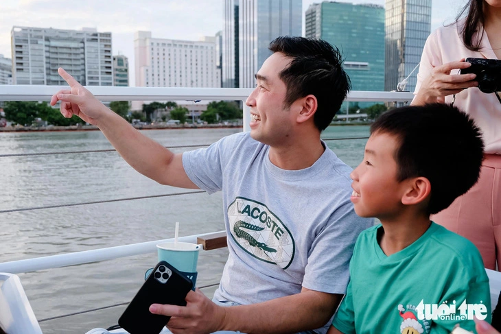 Passengers feel excited to see the picturesque Saigon River while being seated on an open-top double-decker boat. Photo: Phuong Nhi / Tuoi Tre