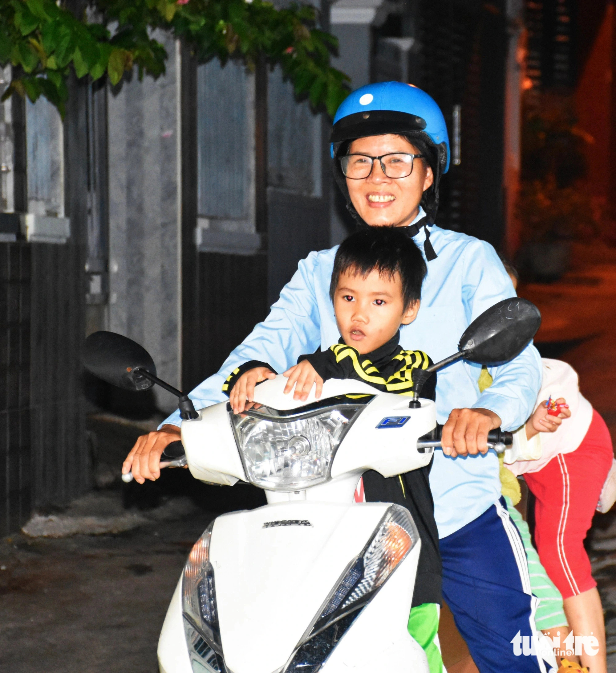 Duc carries her adopted children to her class each day on her motorcycle. She adopted these kids after they were orphaned due to the COVID-19 pandemic. Photo: Tran Hoai / Tuoi Tre