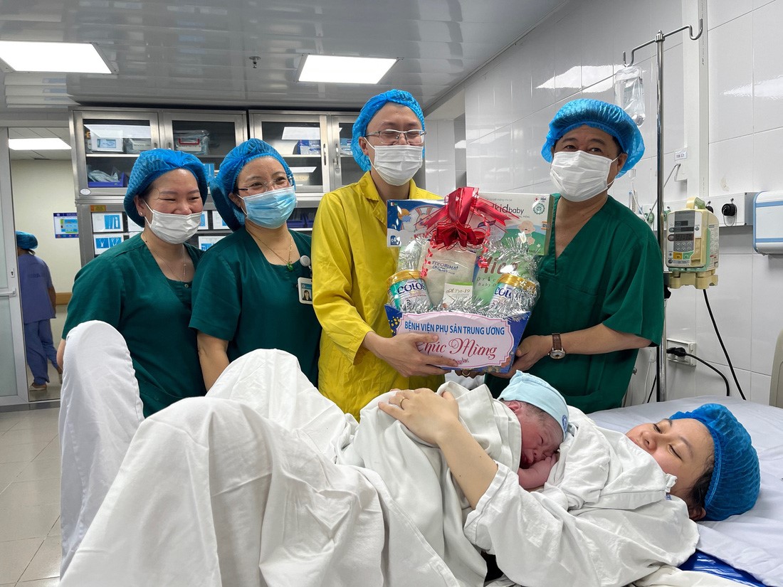 Dinh Anh Tuan (R), head of the Maternal and Child Health Department under the Ministry of Health, gives a present to the family of Tran Huu Nghi, who was born on the 2024 New Year’s Eve. Photo: Hong Ha / Tuoi Tre
