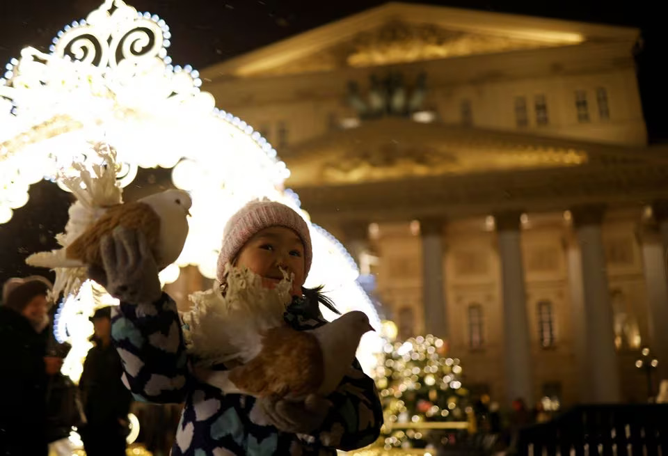 A girl holds pigeons in front of the Bolshoi Theatre during the New Year's Eve celebrations in Moscow, Russia December 31, 2023. Photo: Reuters