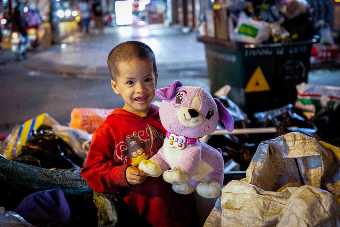 Hoang Khang, smiles when receiving a soft toy from a group of volunteers in Ho Chi Minh City on January 14, 2023. Every night, Khang follows his mother around streets and alleys in the city to pick up scraps for extra income. Photo: Phuong Quyen / Tuoi Tre