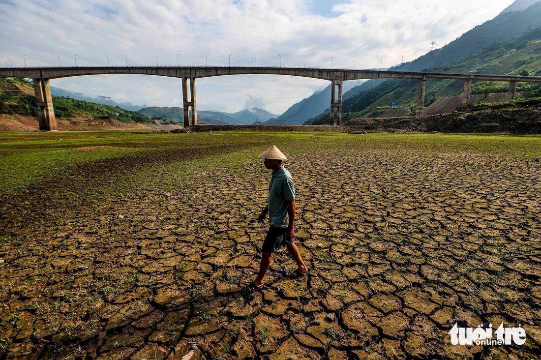 A local in Muong Lay Town in the northern province of Dien Bien walks in the middle of Son La hydroelectric reservoir. Prolonged drought, intense heat, and little rain have caused the water levels in Vietnam's largest hydroelectric reservoir to drop to the ‘dead level,’ greatly affecting the operation, power supply, and people's livelihoods. Photo: Nguyen Khanh / Tuoi Tre