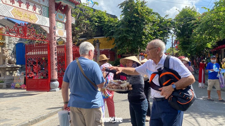 A foreigner (in white T-shirt) saves his friend from a street vendor in the Hoi An Ancient Town in Quang Nam Province. Photo: B.D. / Tuoi Tre