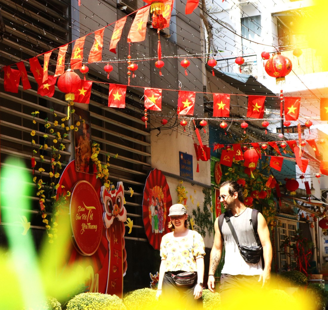 Two foreigners take a walk in an alley donning Tet-themed decorations in Ho Chi Minh City. Photo: Be Hieu / Tuoi Tre