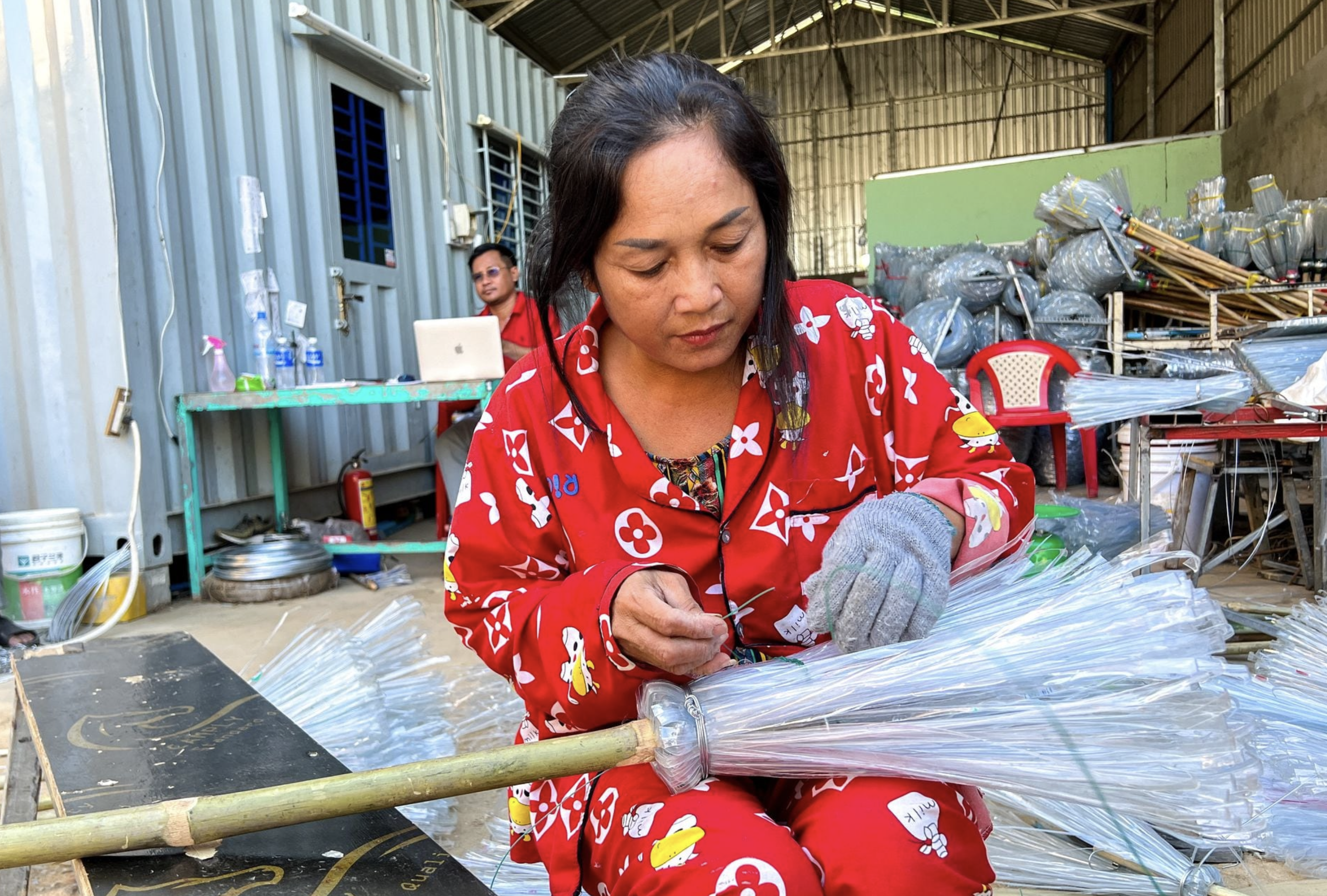 A woman works on a plastic broomstick at a warehouse in Phnom Penh, Cambodia, January 15, 2024. Photo: Reuters