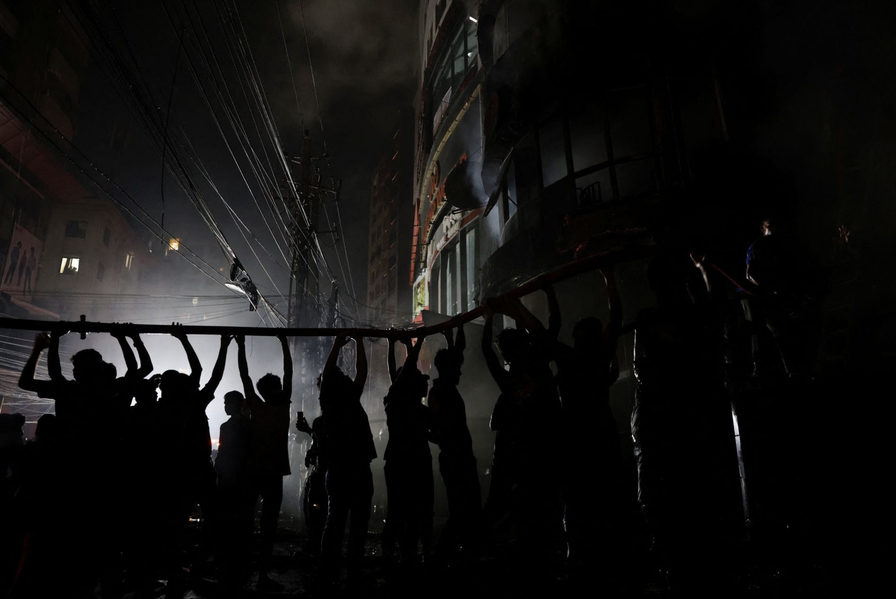 Volunteers hold a water pipe after a fire broke out in a multi-storey building in Dhaka, Bangladesh, February 29, 2024. Photo: Reuters