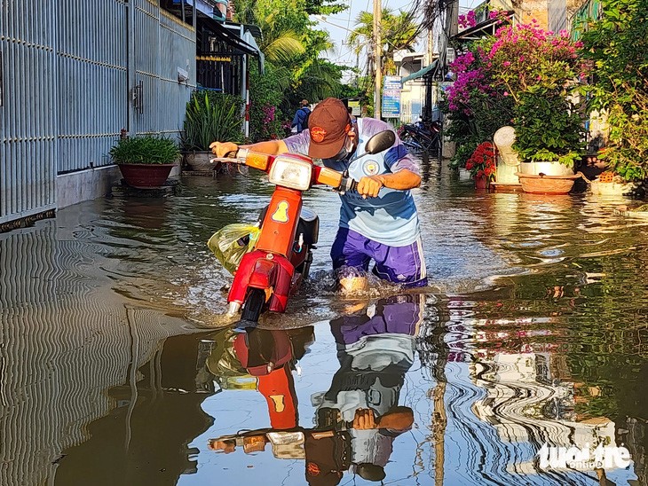 A motorbike breaks down due to flooding triggered by high tide in My Tho City. Photo: Hoai Thuong / Tuoi Tre