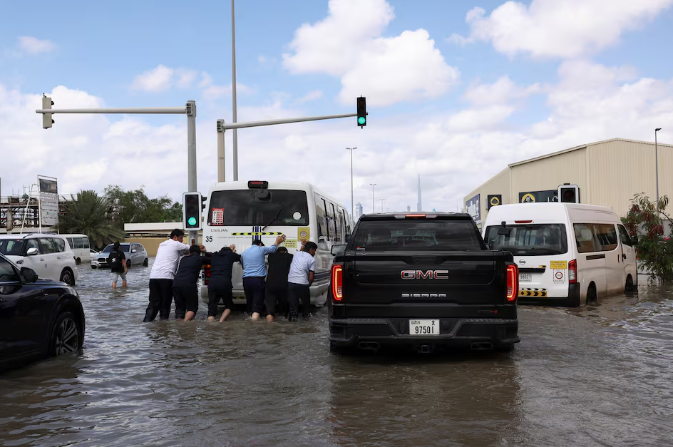 People push a bus through flood water caused by heavy rains, in Dubai, United Arab Emirates, April 17, 2024. Photo: Reuters