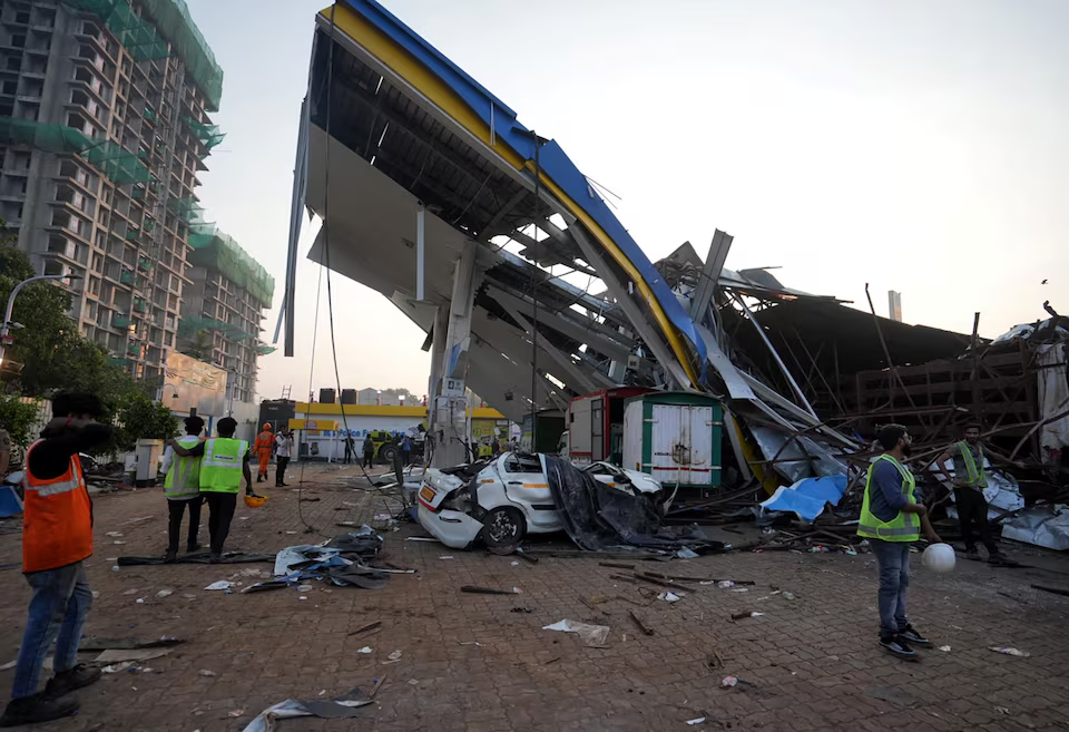 Members of rescue teams stand at a damaged fuel station after a massive billboard fell during a rainstorm in Mumbai, India, May 14, 2024. Photo: Reuters