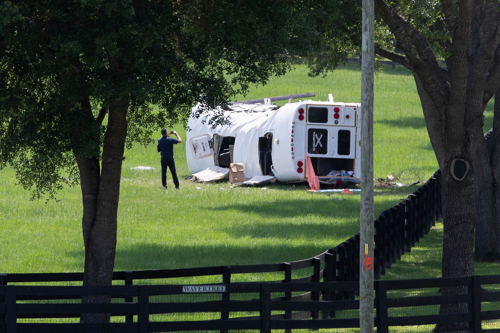 A person takes a picture of the scene where a bus, carrying laborers to a melon farm, overturned in a fatal crash near Dunnellon, Florida, U.S. May 14, 2024. Photo: Reuters