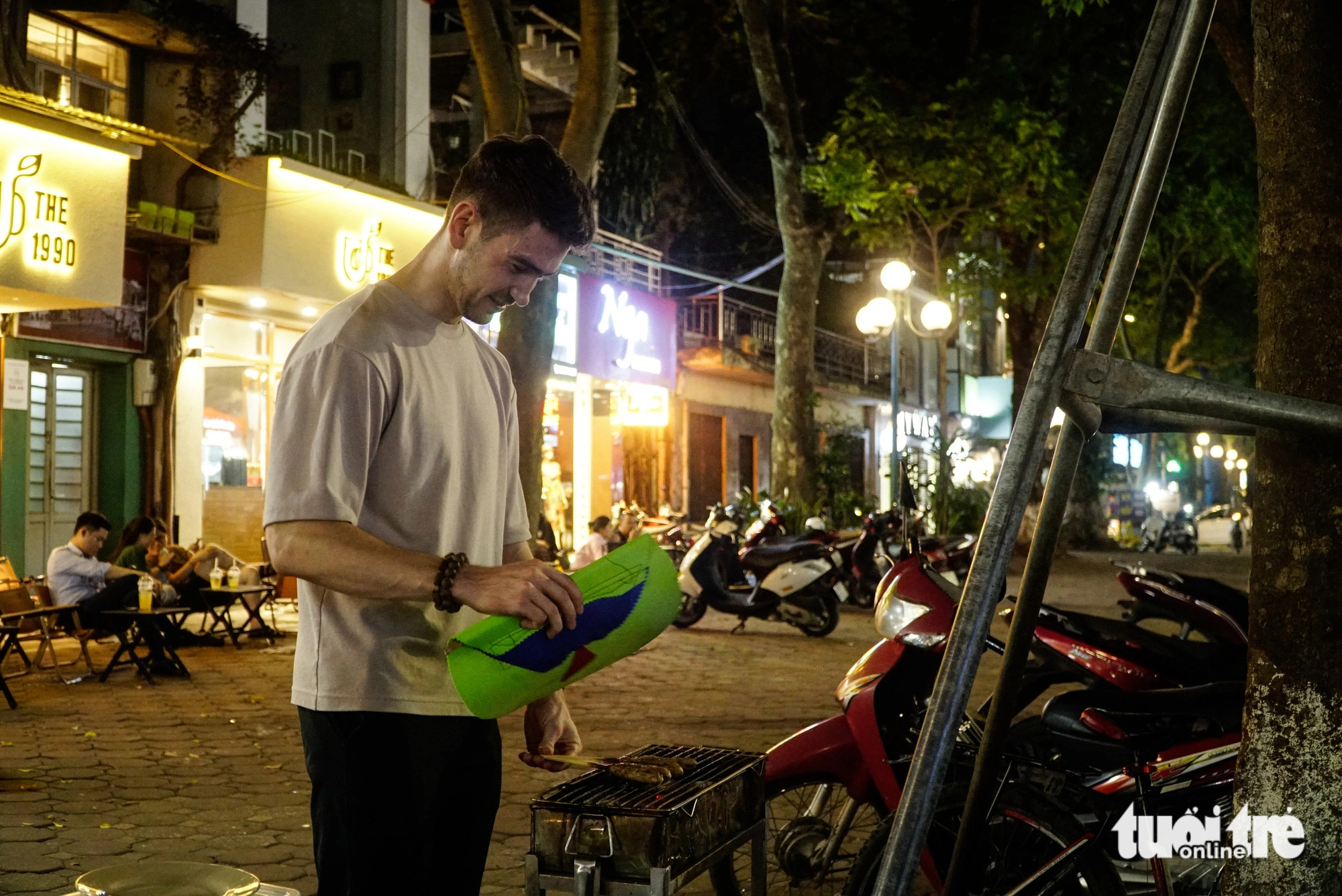 Moritz, a 28-year-old Swiss man, grills ‘nem lụi’ (Vietnamese pork lemongrass skewer) on Phan Dinh Phung Street in Hanoi. Photo: Nguyen Hien / Tuoi Tre