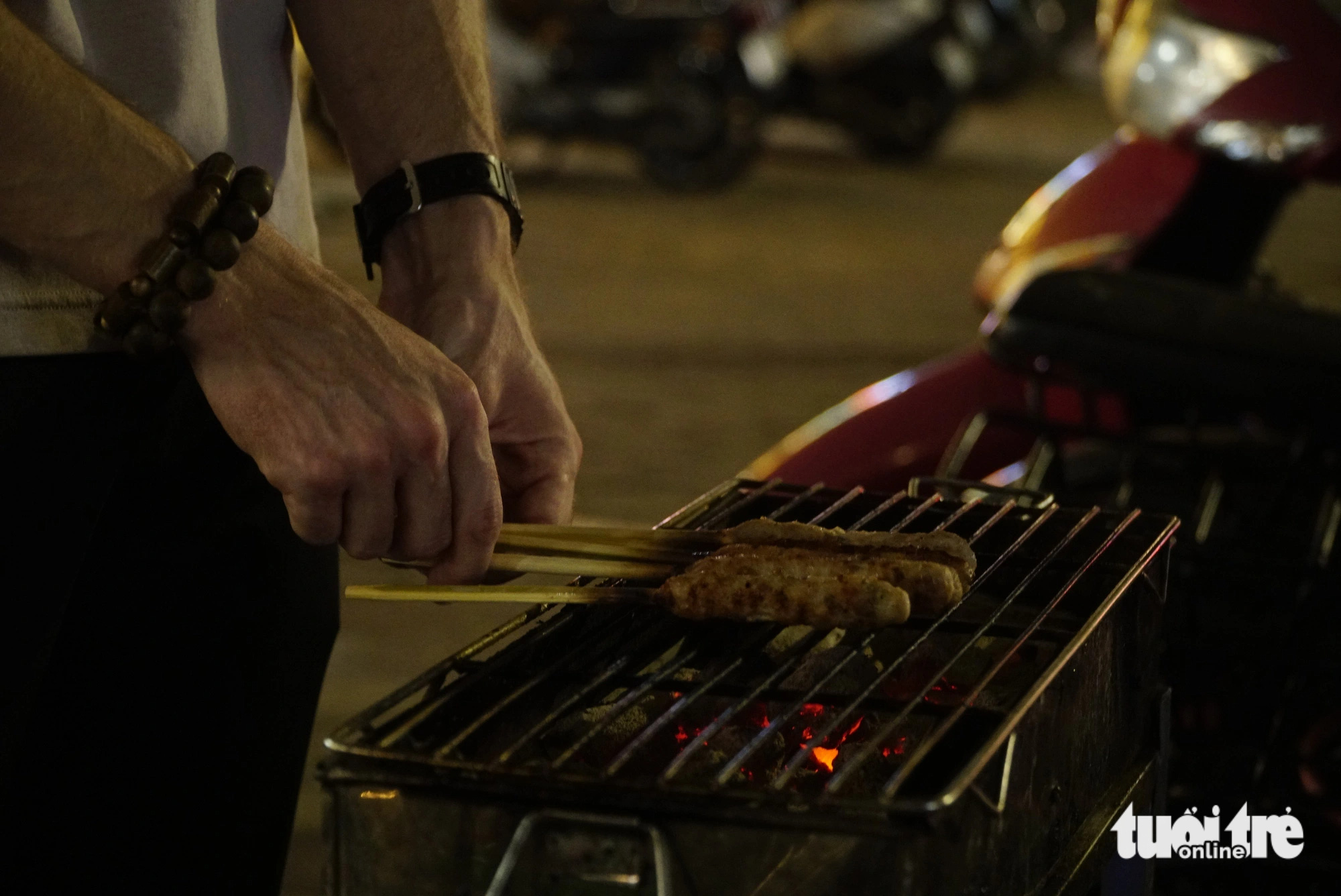 Moritz, a 28-year-old Swiss man, grills ‘nem lụi’ (Vietnamese pork lemongrass skewer) on Phan Dinh Phung Street in Hanoi. Photo: Nguyen Hien / Tuoi Tre