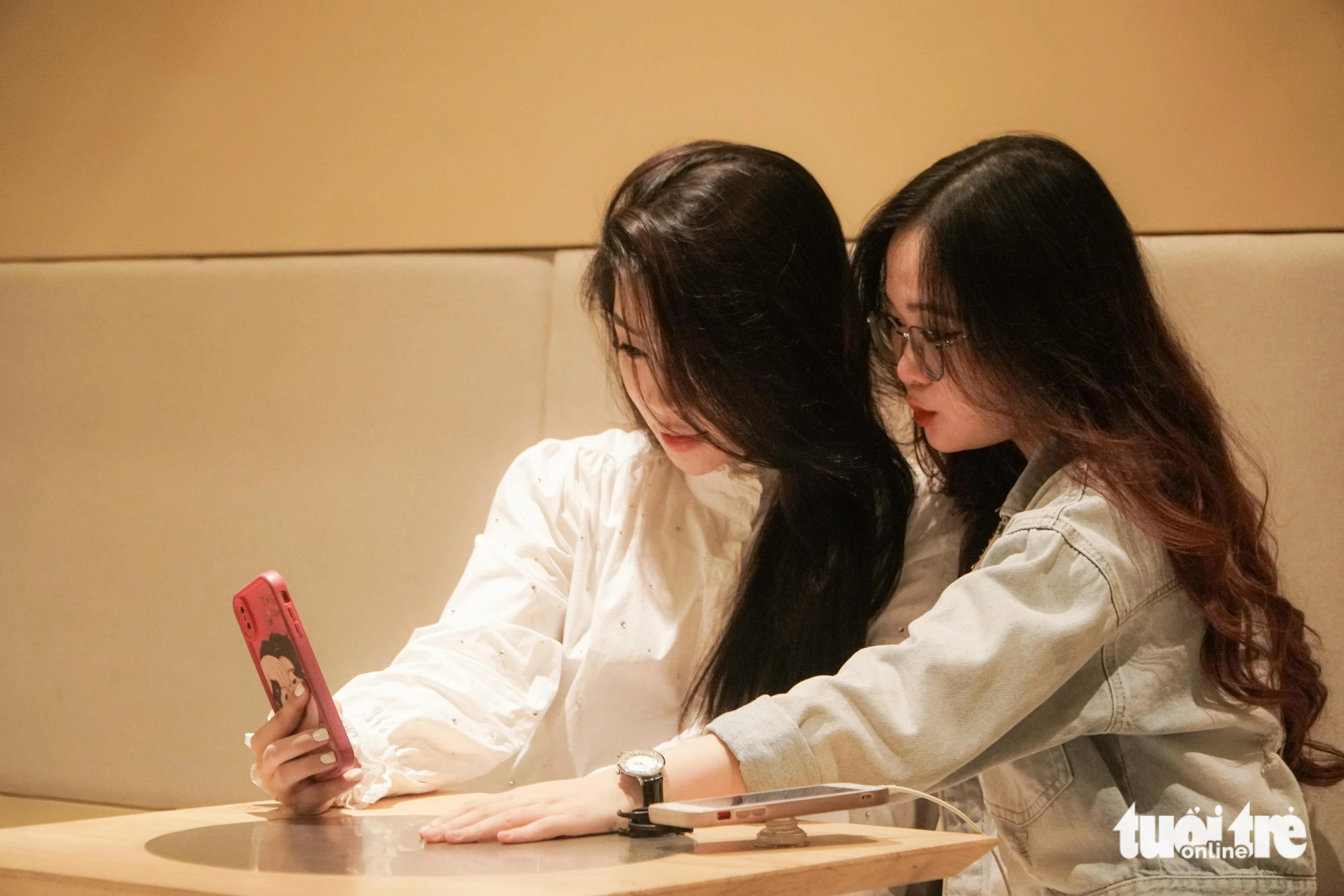 Two customers take selfies at a coffee shop on Tong Dan Street in Hoan Kiem District, Hanoi, at dawn on June 14, 2024. Photo: Pham Tuan / Tuoi Tre