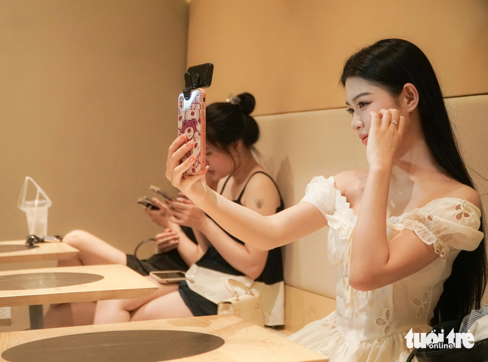 Hoang Yen Nhu takes selfies at a coffee shop on Tong Dan Street in Hoan Kiem District, Hanoi, at dawn on June 14, 2024. Photo: Pham Tuan / Tuoi Tre