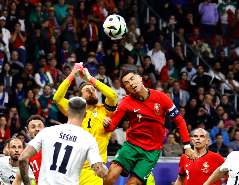 Soccer Football - Euro 2024 - Round of 16 - Portugal v Slovenia - Frankfurt Arena, Frankfurt, Germany - July 1, 2024 Slovenia's Jan Oblak in action with Portugal's Cristiano Ronaldo. Photo: Reuters