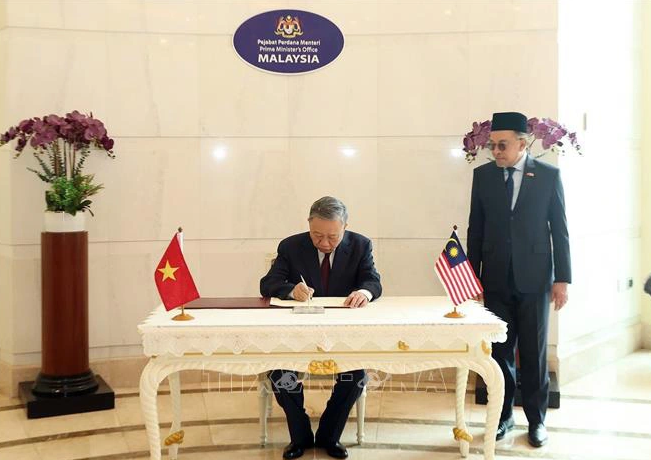  Vietnamese Party chief To Lam writes in a guest book. Photo: Vietnam News Agency
