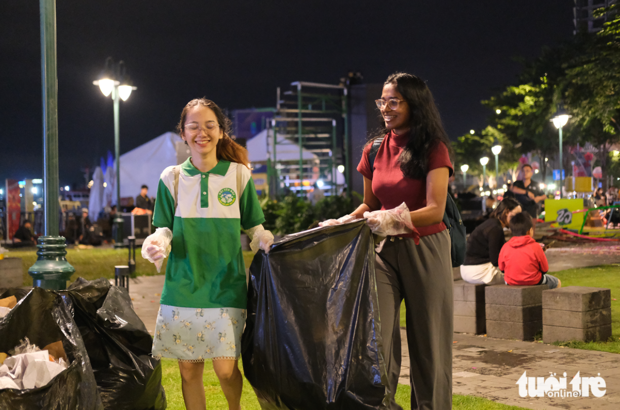 Dulani (R) from Sri Lanka joins hands with young people in the city to clean up a trash-flooded area in downtown Ho Chi Minh City. Photo: Nguyen Khang / Tuoi Tre