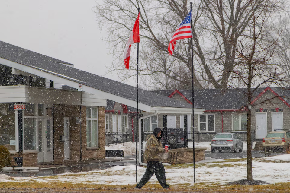 A person walks during a snow fall as a Canadian and a U.S. flag wave in the wind in Niagara Falls, Ontario, Canada, January 31, 2025. Photo: Reuters