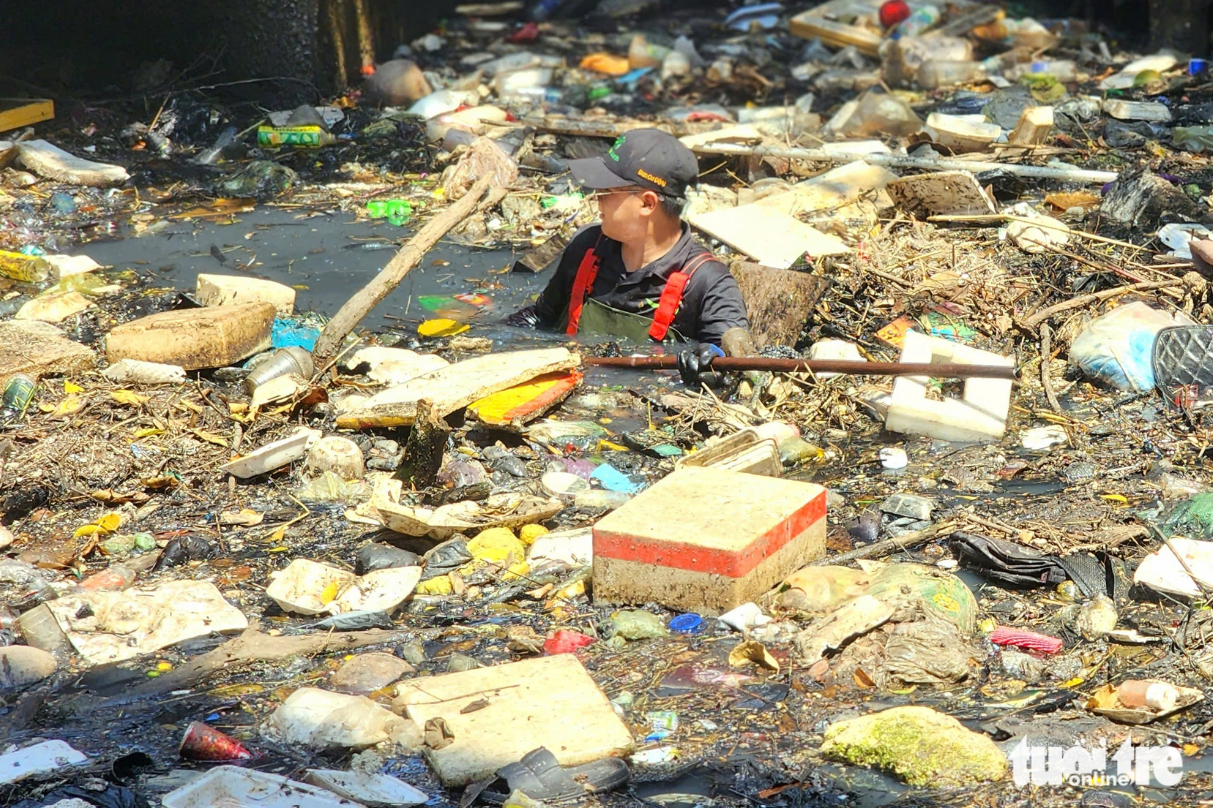 Do Phuong Nam, a volunteer of the Saigon Xanh Club, collects garbage from a polluted section of Hy Vong Canal on March 1, 2025. Photo: Ngoc Khai / Tuoi Tre