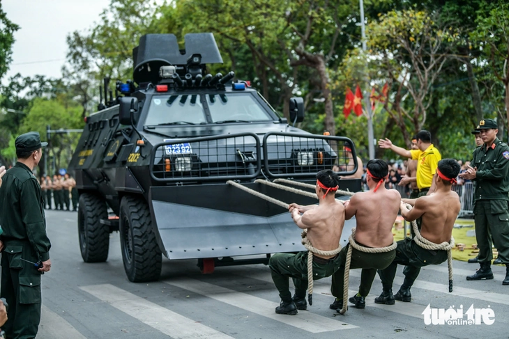 Three public security officers perform a daring stunt by pulling a specialized vehicle with three ropes during a rehearsal in Hanoi, Vietnam, March 7, 2025. Photo: Nam Tran / Tuoi Tre